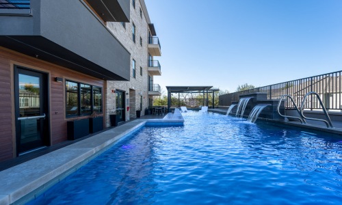 Large sparkling blue pool with a large pool deck and lounge chairs