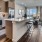 Large well lit kitchen with dark wood floors and granite countertops with stainless steel appliances. 