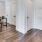 Spacious well lit open floor plan concept with dark wood floors and access to the kitchen and dining area. 