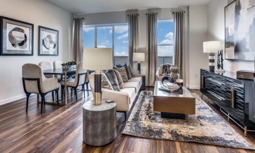 Spacious and well lit living room with wood floors and large windows with a views of Dallas at The Drake