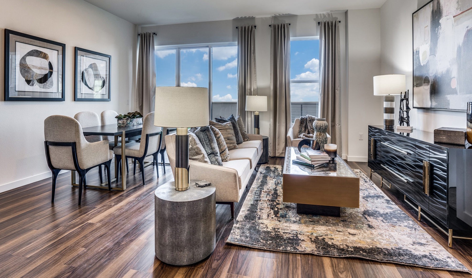 Spacious and well lit living room with wood floors and large windows with a views of Dallas at The Drake